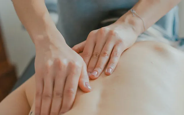 A therapist working on a client's shoulder during a treatment session