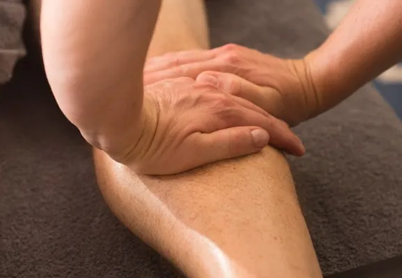 Close-up of a therapist's hands working along a client's lower leg