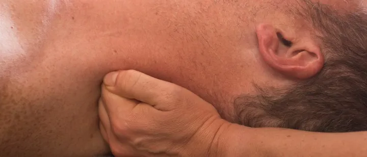 A sports massage therapist releasing tension at the side of a client's neck